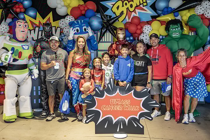 Fundraising team posing for a photo in front of a superhero-themed backdrop.